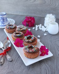 Obraz na płótnie Canvas pumpkin cupcakes with chocolate cream and colored sprinkles