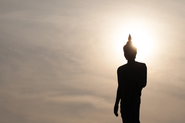 Silhouette of Buddha statue in front of Sun