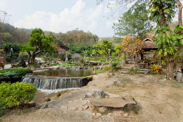 Fototapeta na wymiar Forest with small waterfall of river in old gaden of green village