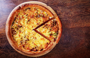 Pizza with beef stuffing, leek and cheese served on wooden table