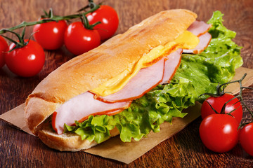 Sandwich from fresh baguette on wooden background