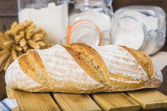 Pan de masa madre natural hecho a mano por un panadero tradicional decorado con espigas de trigo y centeno