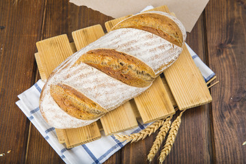 Pan de masa madre natural hecho a mano por un panadero tradicional decorado con espigas de trigo y centeno