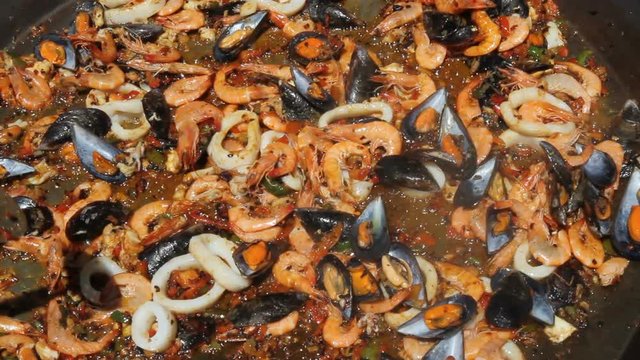 Sofriendo los ingredientes basicos para la preparacion de una paella de marisco al aire libre