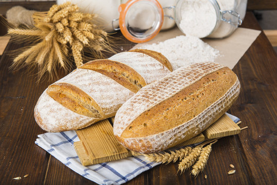 Pan de masa madre natural hecho a mano por un panadero tradicional decorado con espigas de trigo y centeno