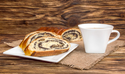 Poppy roll with cup of tea on the wooden table