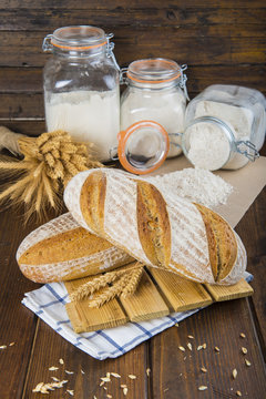 Pan de masa madre natural hecho a mano por un panadero tradicional decorado con espigas de trigo y centeno