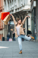 Young woman jumping at the street happy after shopping