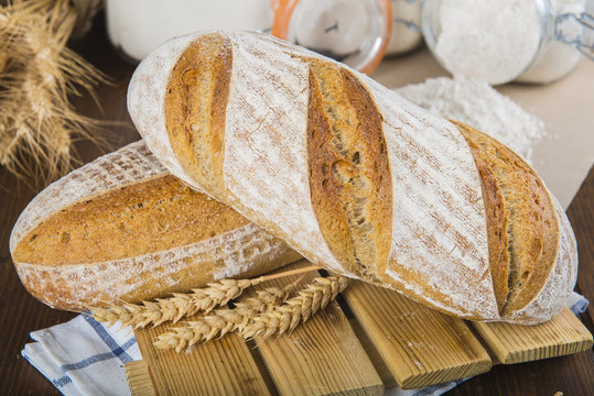 Pan de masa madre natural hecho a mano por un panadero tradicional decorado con espigas de trigo y centeno