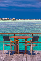 Chairs and table on tropical island with sandy beach and tourquise clear water, Maldives