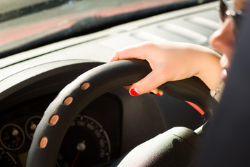 pretty girl riding a car; looking concentrated (focus on hand)