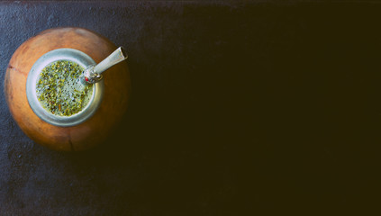 Yerba herb mate in calabash on black background. Top view