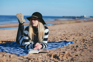 girl reading a book lying on the beach