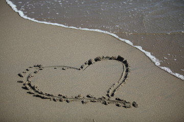 Shape of a heart on the beach, soft wave of the sea.