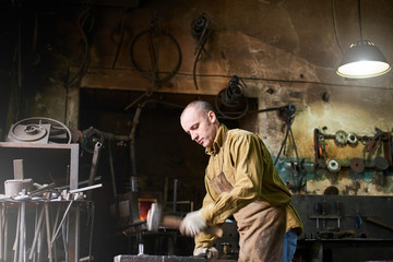 The blacksmith in the production process of metal products handmade in the workshop