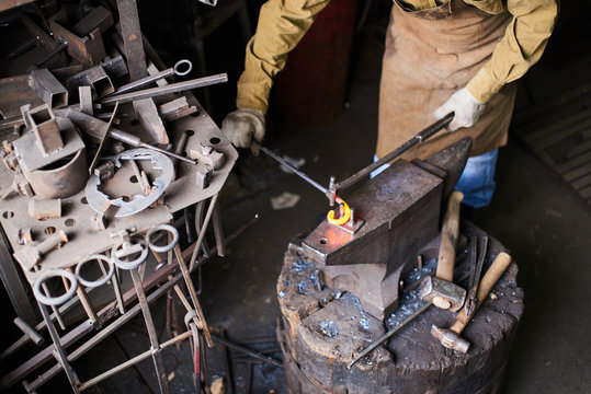 Male hands in the production process of metal products handmade on the anvil