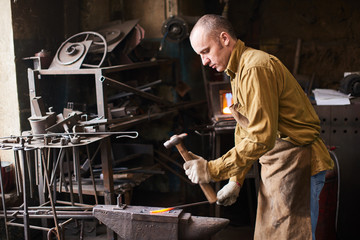 The blacksmith in the production process of metal products handmade in the workshop