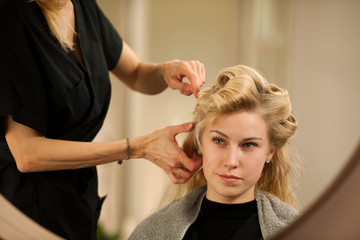 Obraz na płótnie Canvas professional hair stylist at work - hairdresser doing hairstyle