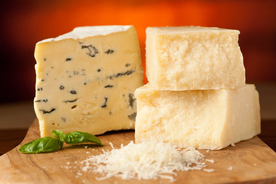 pieces of blue cheese and parmesan on a wooden cutting board bei