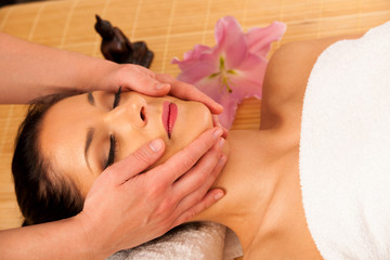 Obraz na płótnie Canvas Beautiful young woman having a face massage in wellness studio -