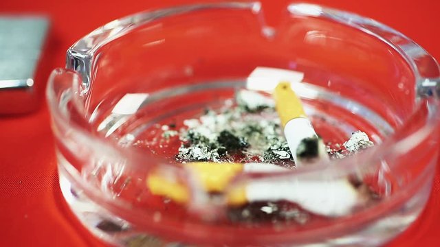 Female putting cigarette butt in ashtray on the table, smoking addiction, habit