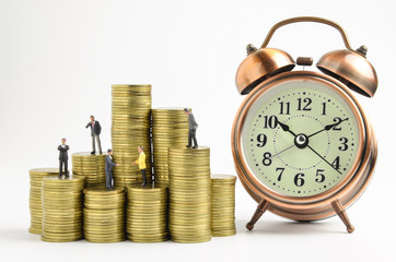 business miniature people and clock on stack of coins
