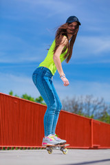 Teen girl skater riding skateboard on street.