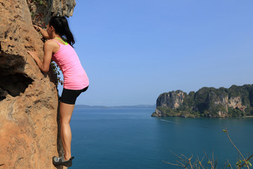 free solo woman rock climber climbing at seaside mountain rock wall