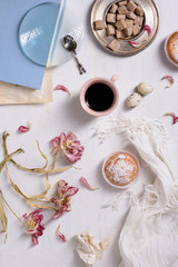 Cup of espresso and cupcake and beautifully faded flowers over white background. Top view.
