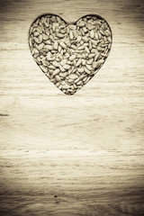 Fototapeta na wymiar Heart shaped sunflower seeds on wood surface