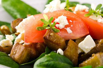 Eggplant salad with tomatoes, feta cheese, spinach and greens