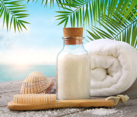 Fluffy towels with sea salt and seashells on beach table