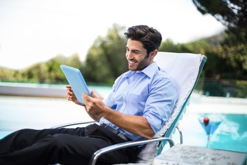 Smart man using digital tablet near pool