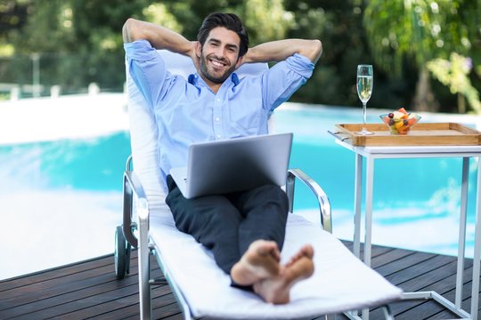 Smart man with a laptop relaxing on sun lounger
