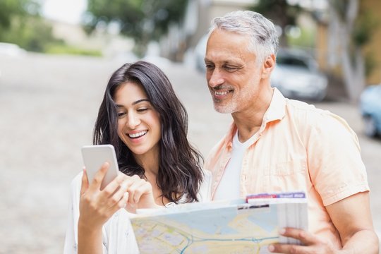 Couple using phone while holding map