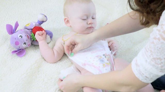 Mom changes the diaper of a small baby
