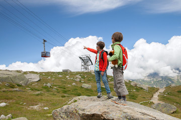 Two boys look at cabin of cable car in european mountains