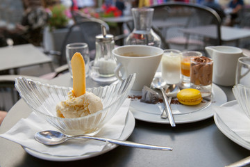 Vanilla ice cream with cookie and cup of coffee are on the table of street cafe