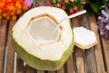 Young coconut with flower on wooden table