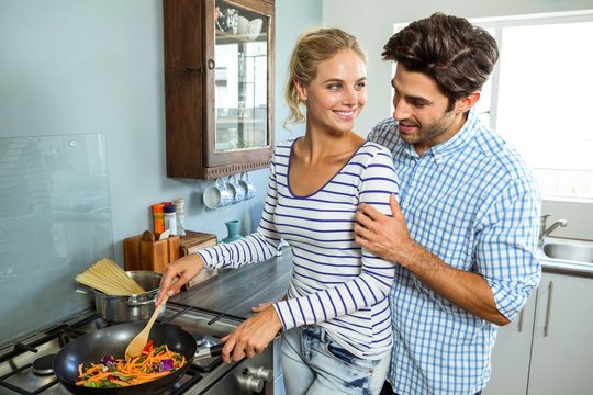 Young couple preparing food together in kitchen 