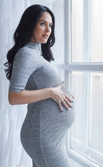 Pregnant brunette woman in a grey dress.