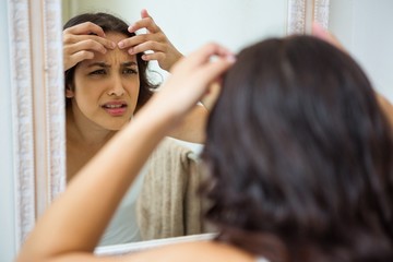 Naklejka premium Woman popping her pimple in bathroom