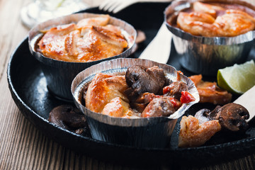 Steak and mushroom pot pies in  aluminum foil dishes on picnic table