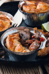 Steak and mushroom pot pies in  aluminum foil dishes on picnic table
