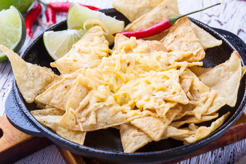 Tortilla chips  with cheese, chili pepper, lime on a wooden table