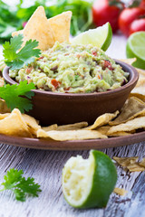 Homemade guacamole sauce and corn chips in ceramic bowl