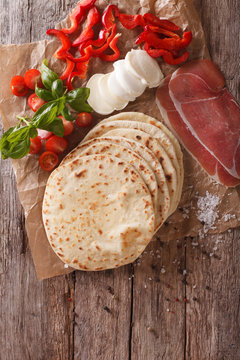 Italian piadina flatbread, ham, cheese and vegetables close-up. Vertical top view
