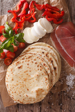 Italian freshly baked piadina with ingredients close-up. vertical top view
