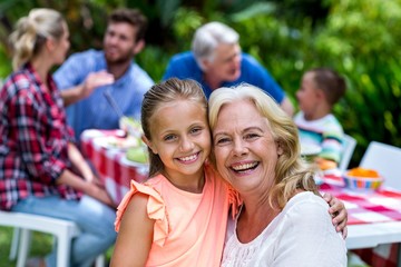 Smiling granny carrying girl during breakfast at yard 