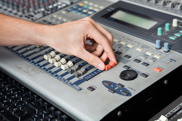Professional's Hand Working On Audio Mixer In Studio